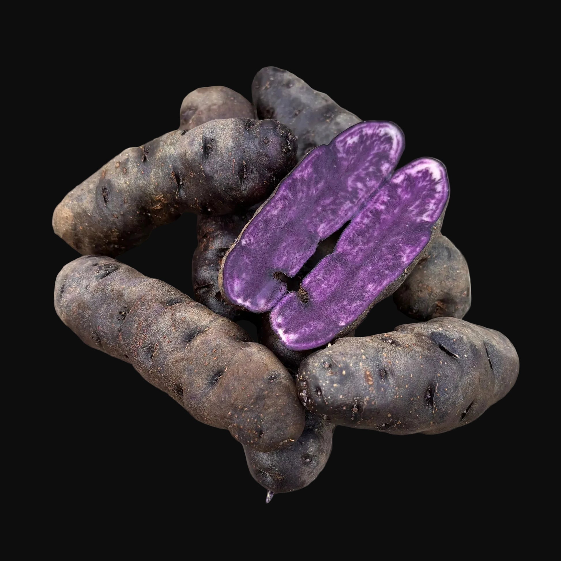 Purple potatoes on a wooden surface with one sliced open to reveal purple flesh.